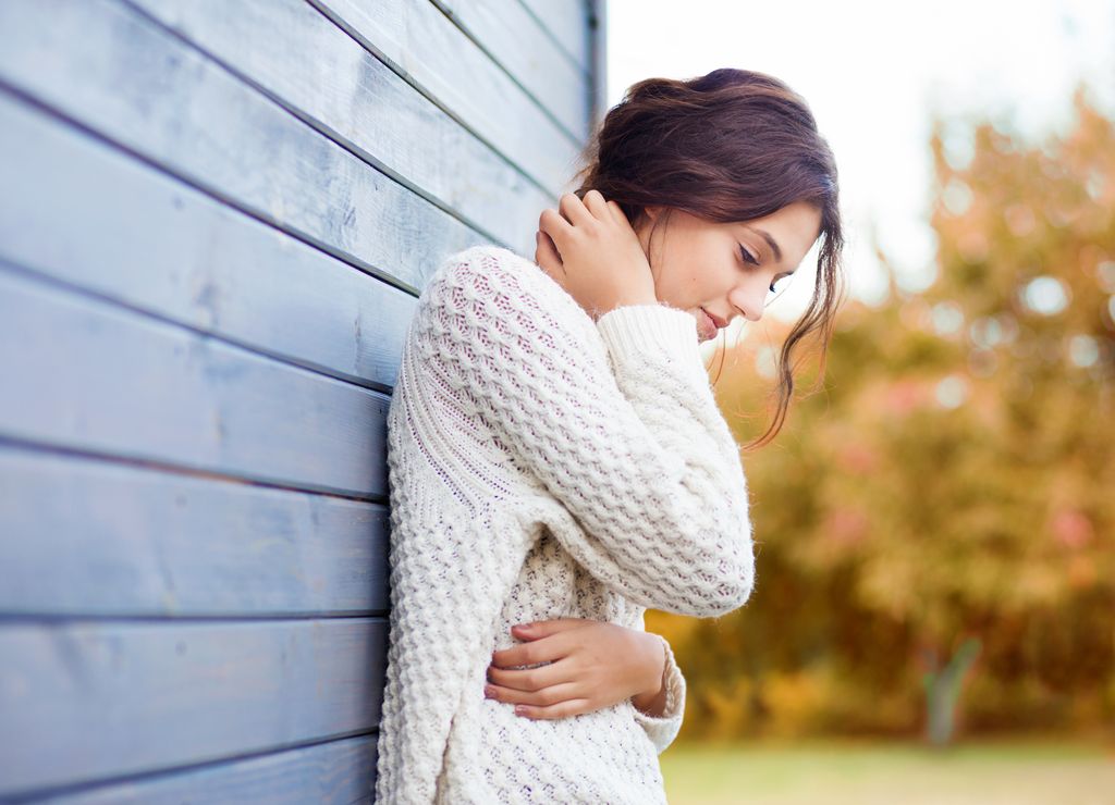 mujer pensativa apoyada en la pared