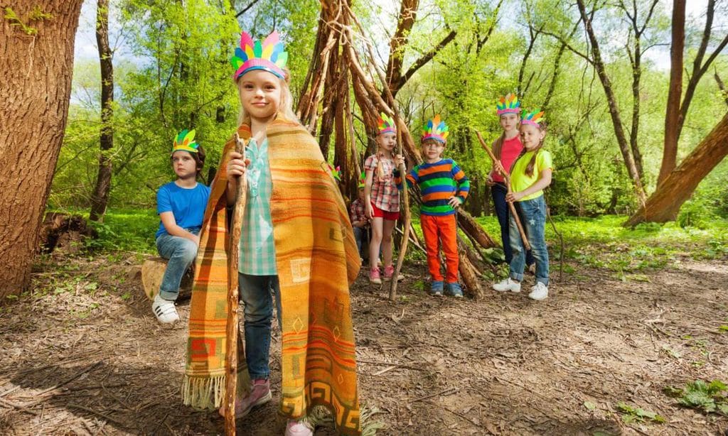 grupo de ni os disfrazados jugando con la naturaleza tras crear una fortaleza