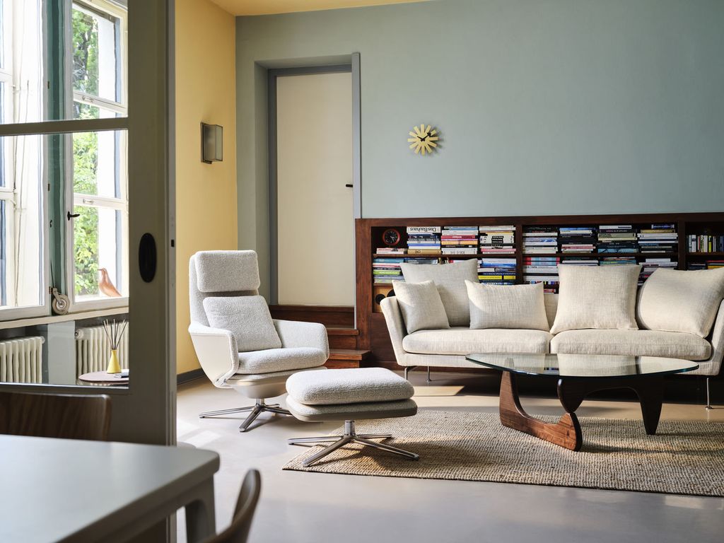 Salón con sofá blanco, chaise longue, alfombra y librería baja de madera