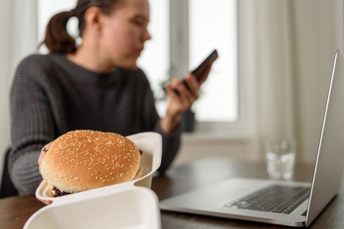 mujer comiendo una hamburguesa