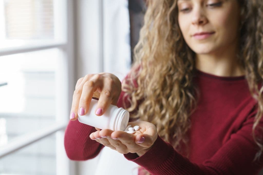 mujer joven con un bote de suplementos alimenticios