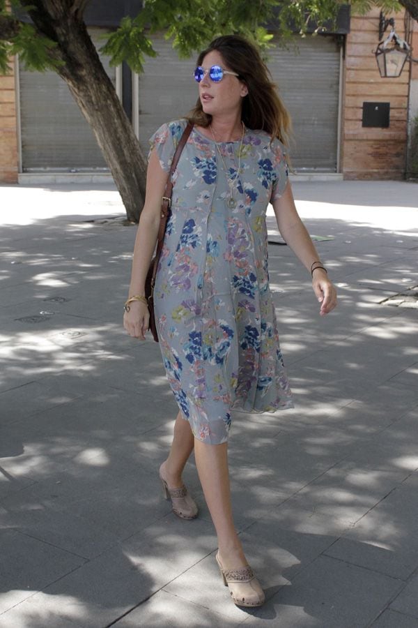 Lourdes, con un veraniego vestido de flores y unas gafas de sol de espejo, ha esperado a su marido en el interior del hospital
