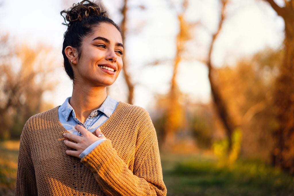 mujer pensativa y sonriente al aire libre