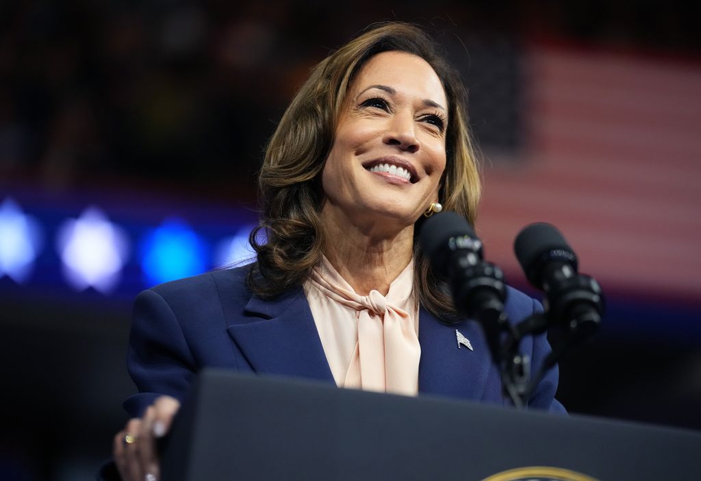 Primer plano de Kamala Harris dando un discurso con blazer azul marino y clusa rosa