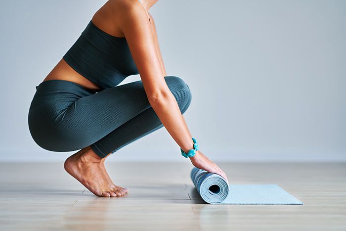 mujer extendiendo una esterilla para hacer pilates o yoga