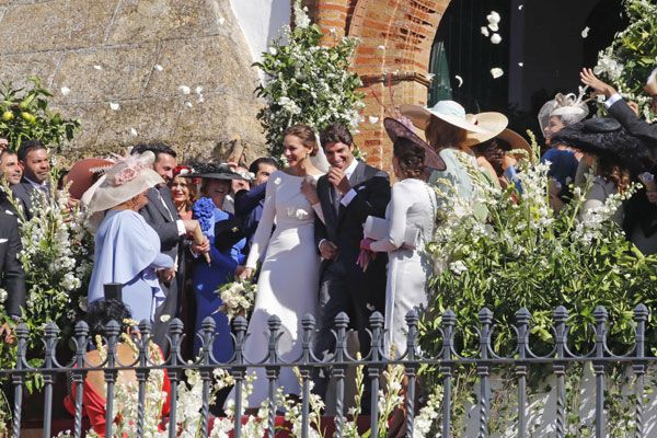 Los novios a la salida de iglesia bajo una lluvia de pétalos
