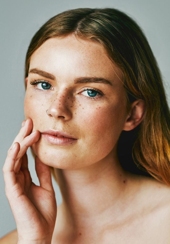 Primer plano mujer pelo suelto ojos azules y pecas