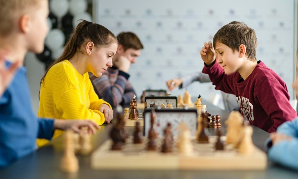 kids of different ages boys and girls playing chess on the tournament in the chess club