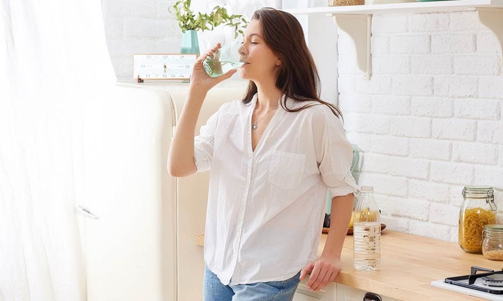 Mujer bebe agua para quitar el hipo