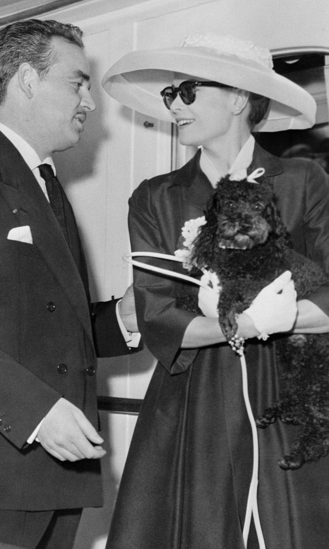 El Príncipe Rainiero III de Mónaco se une a su prometida, la actriz estadounidense Grace Kelly, quien sostiene a su perro Oliver, a bordo del yate principesco "Deo Juvante II" el 12 de abril de 1956 en el puerto de Montecarlo, mientras Grace Kelly llega desde Estados Unidos para su ceremonia de boda, programada para el 19 de abril de 1956.