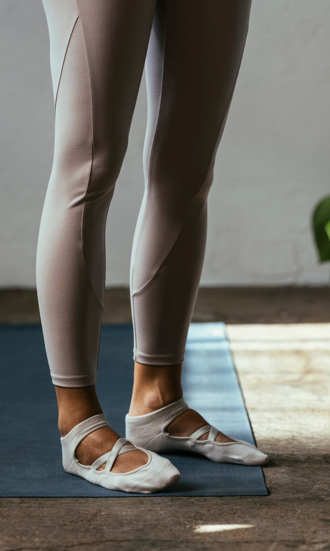 Mujer practicando yoga sobre una esterilla con calcetines en sus pies.