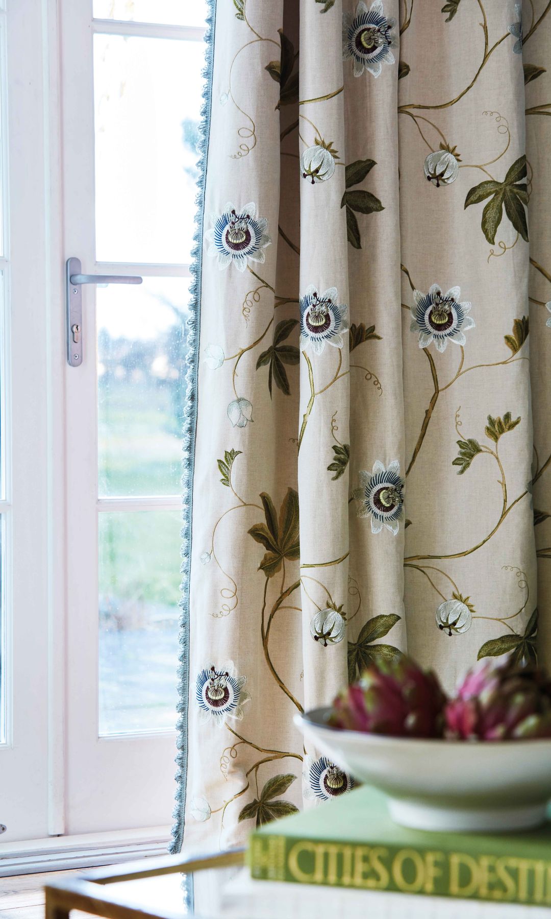 Ventana con perfilaría blanca y cortinas beiges con estampado de flores