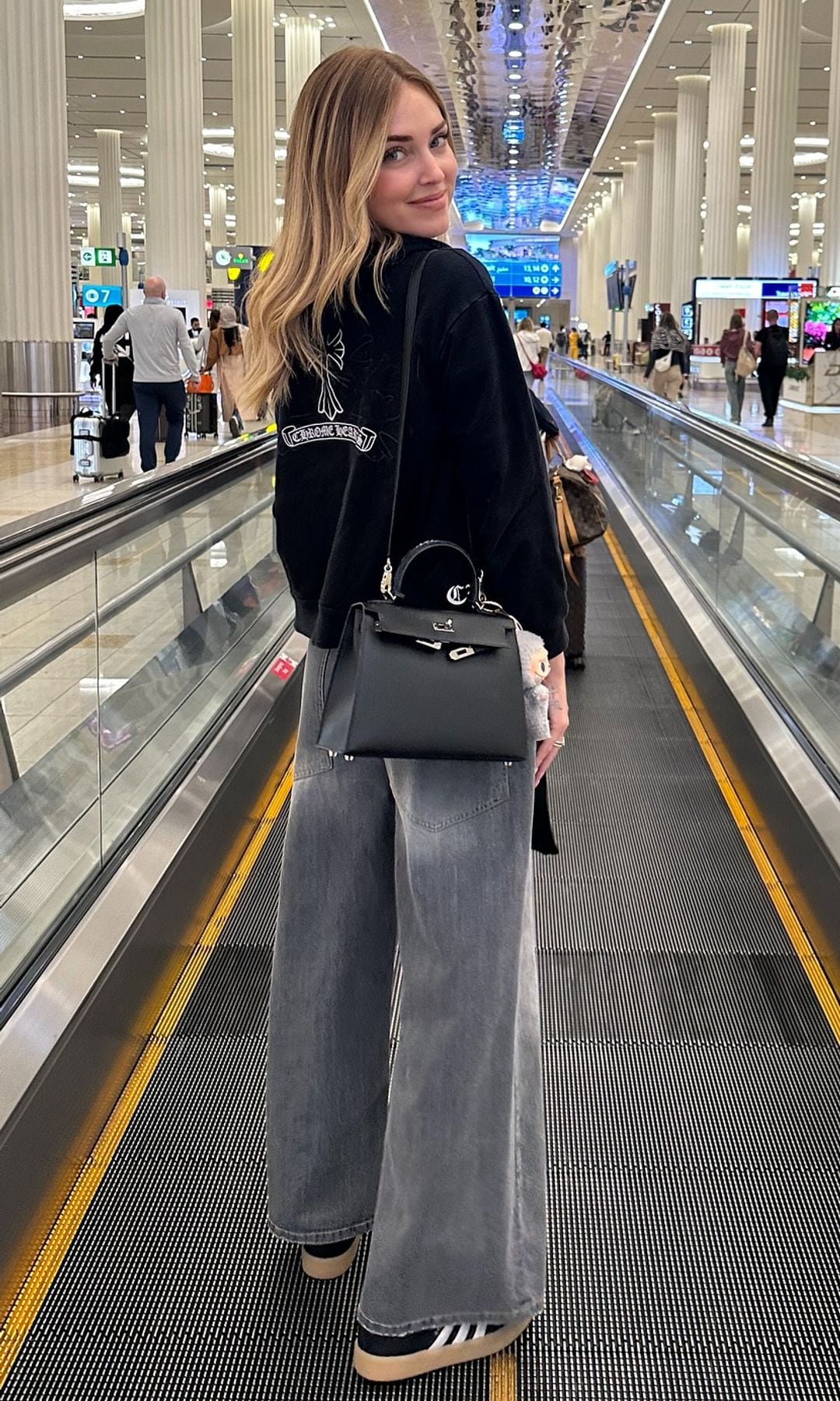 Chiara Ferragni con pantalones vaqueros, sudadera, bolso y zapatillas negras de Adidas