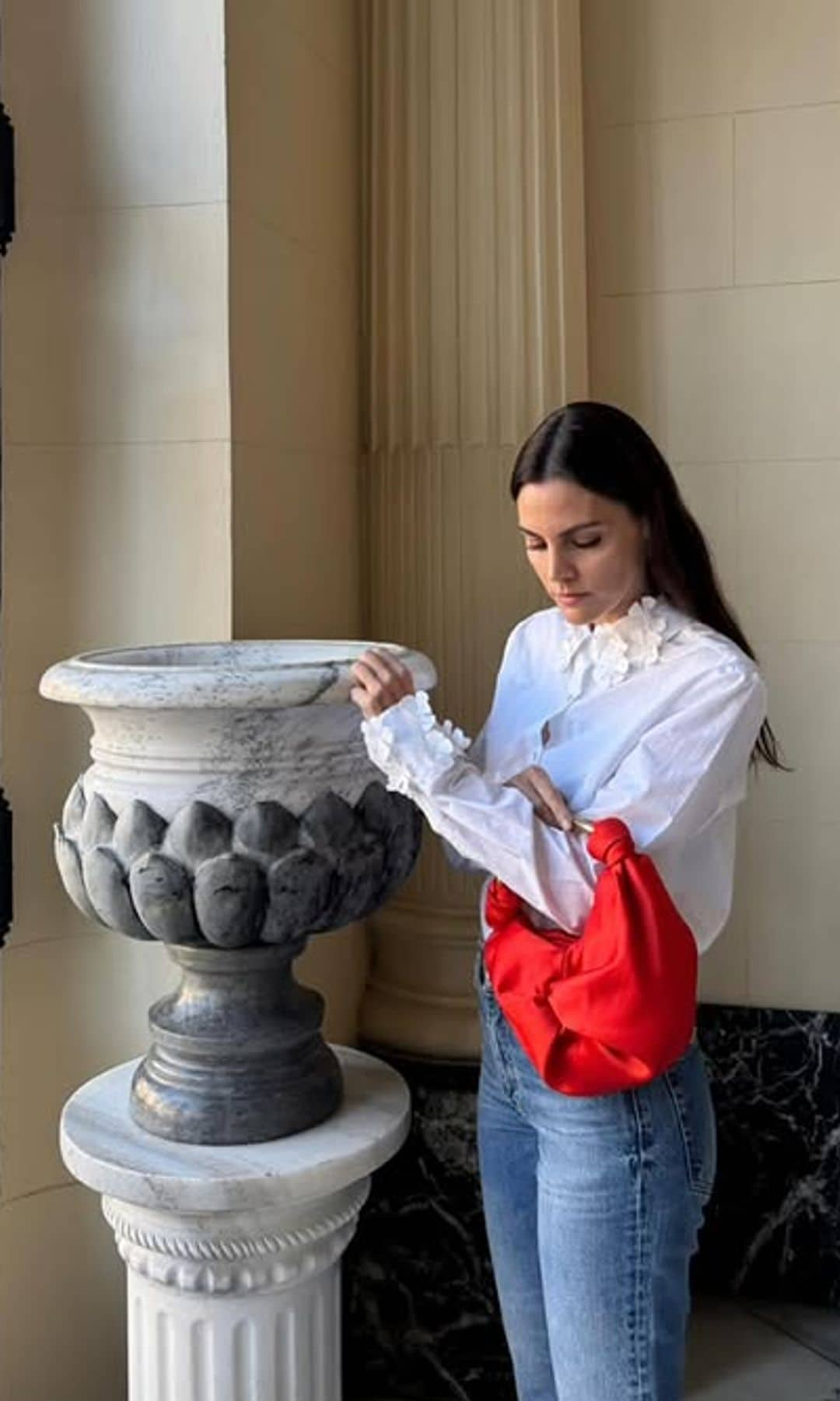 Amaia Salamanca con blusa blanca, vaqueros y bolso rojo con asa metalizada