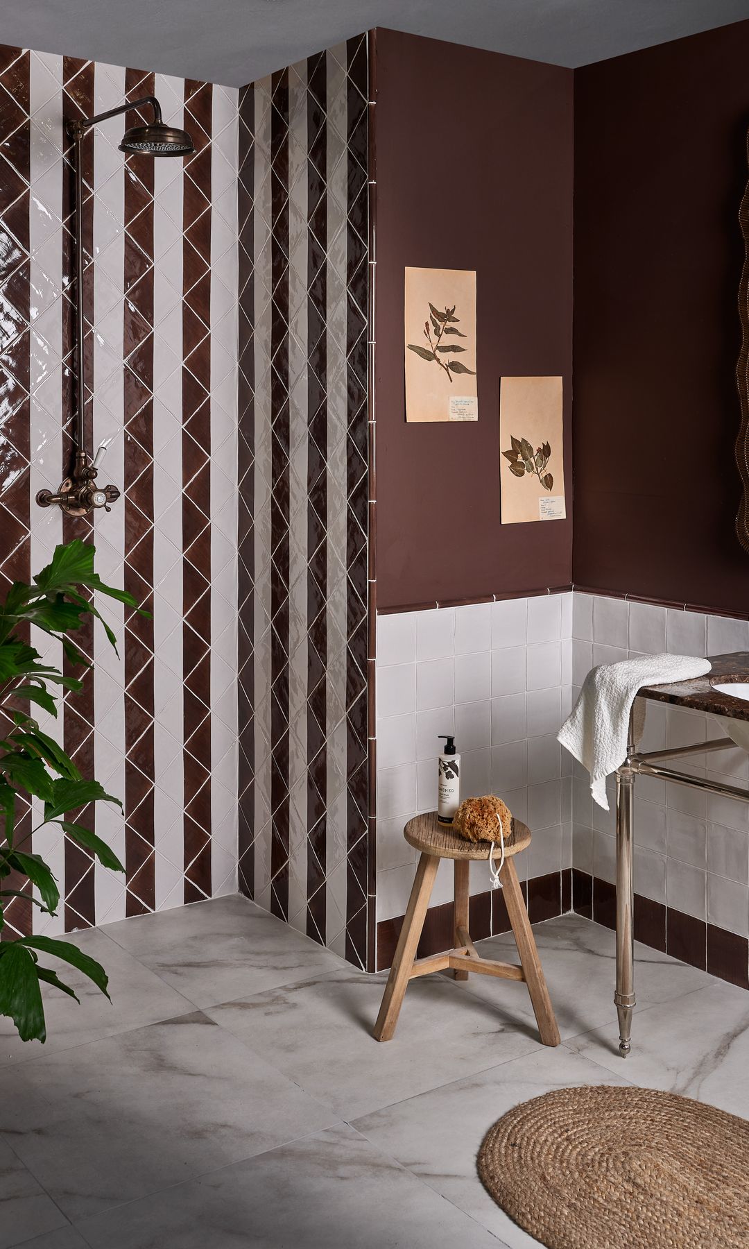 Baño con ducha con azulejos bicolores, zócalo blanco y paredes marrones