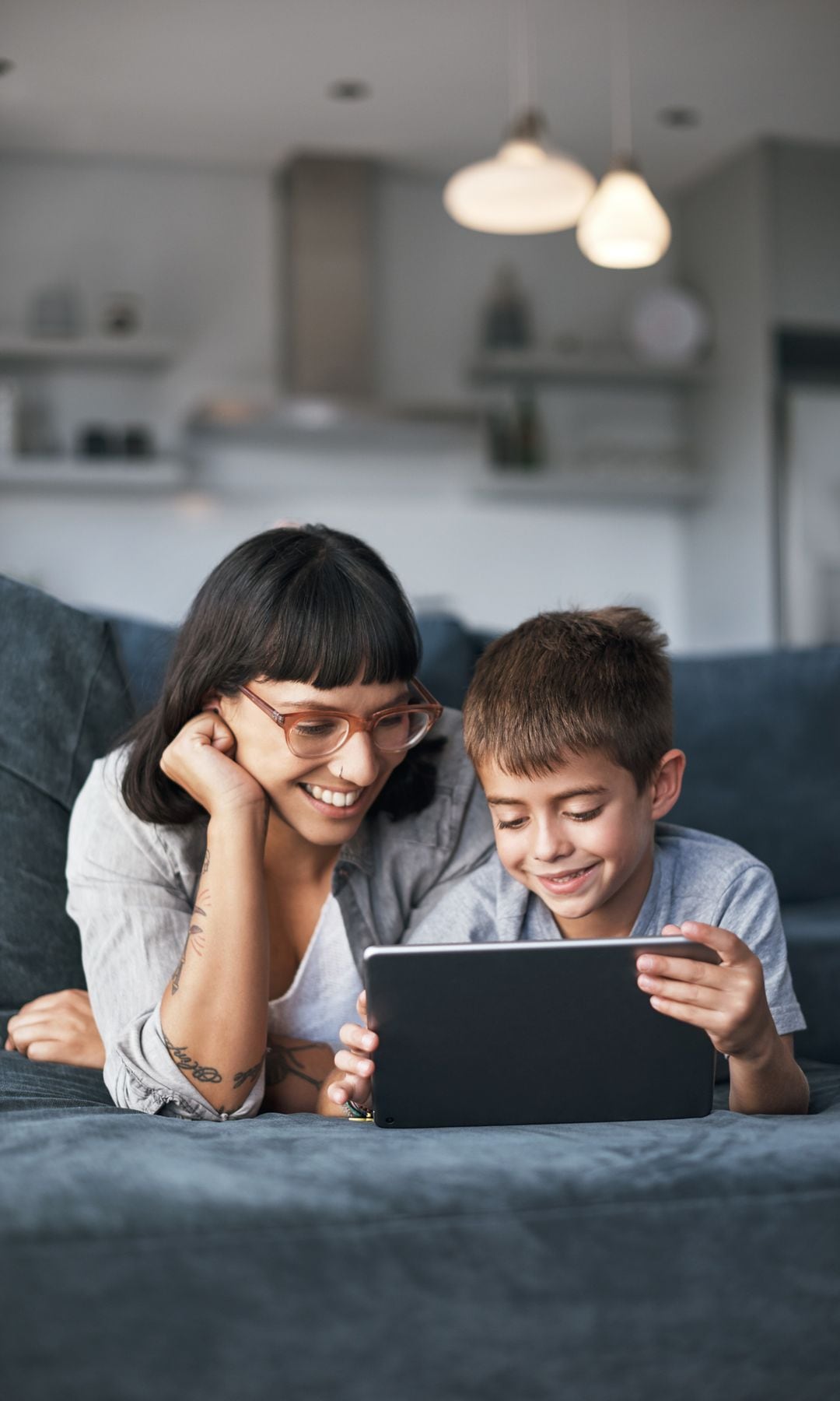 Madre e hijo utilizan una tablet en el sofá de casa