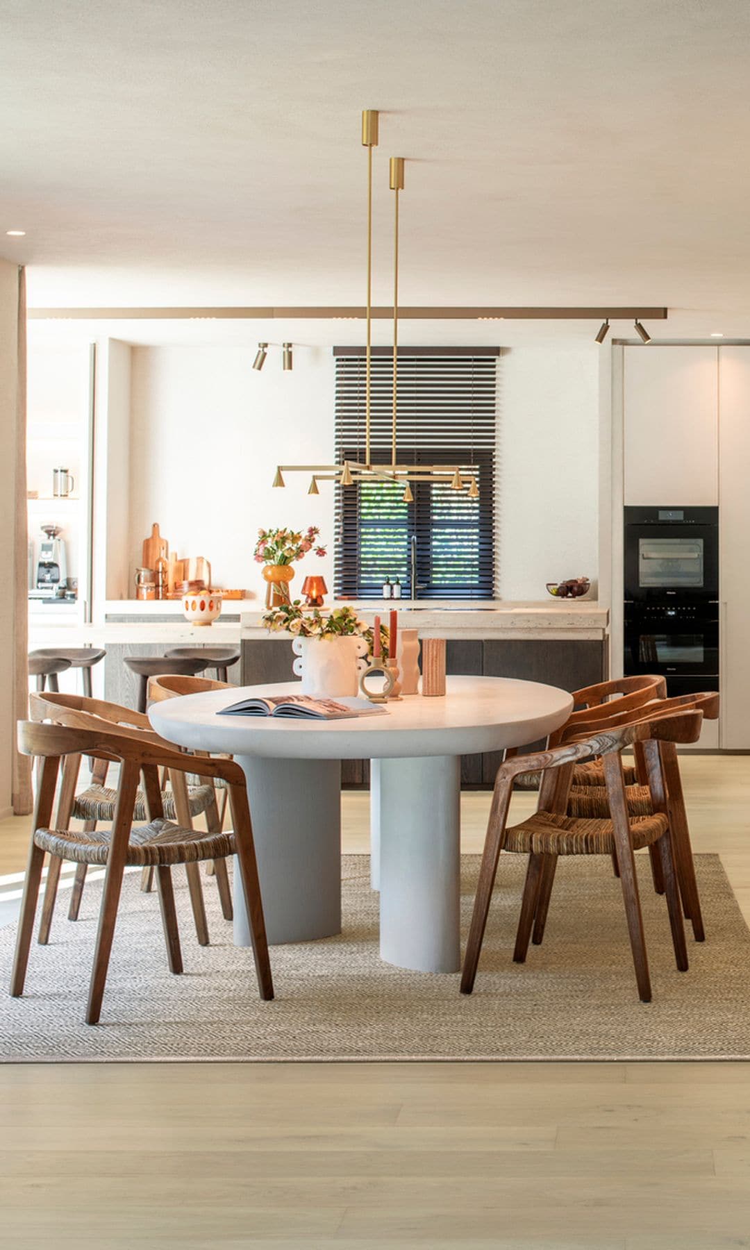 Cocina abierta al comedor con mesa blanca, sillas de madera y parquet 