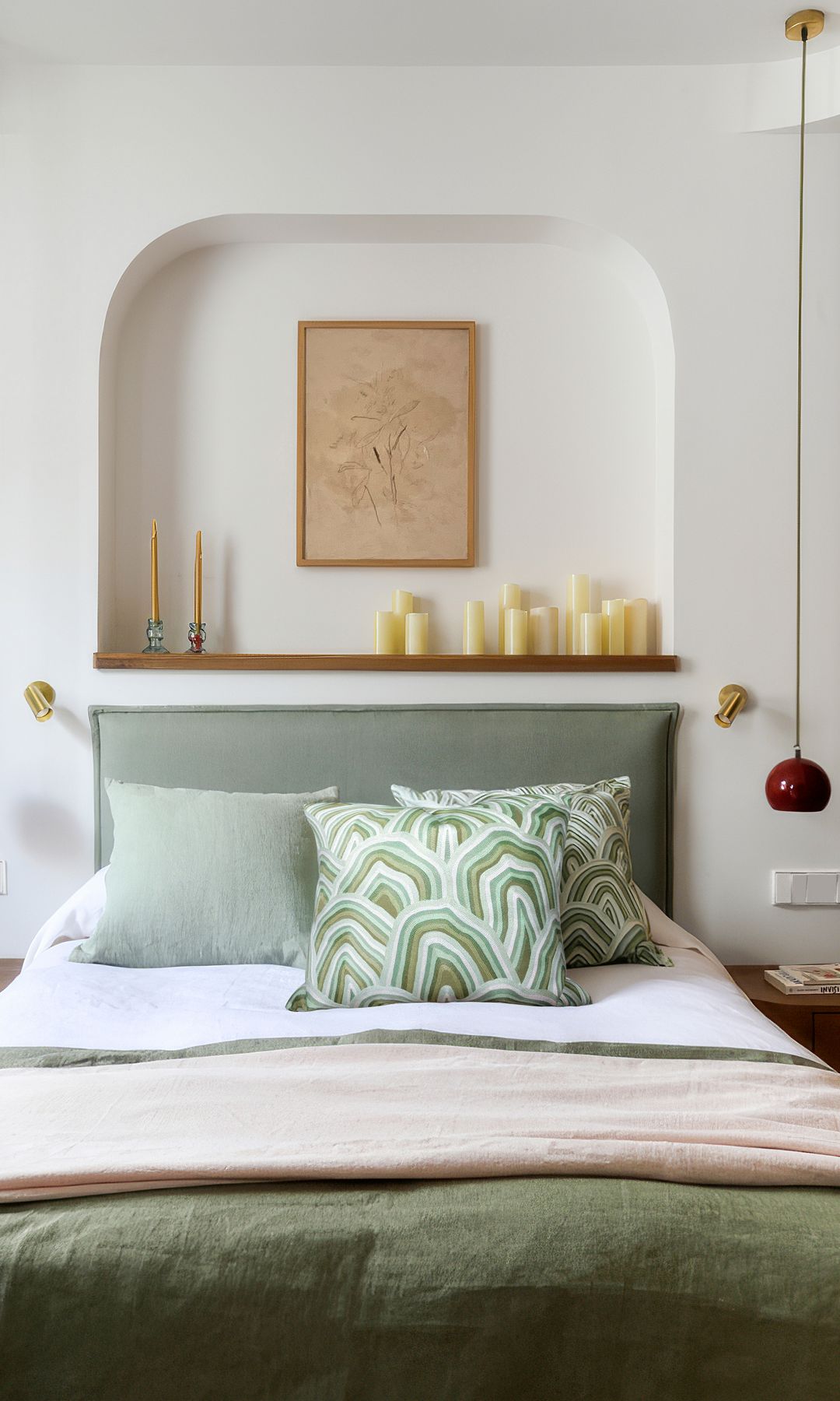 Dormitorio con hornacina en la pared del cabecero con balda de madera, cuadro y velas, ropa de cama verde