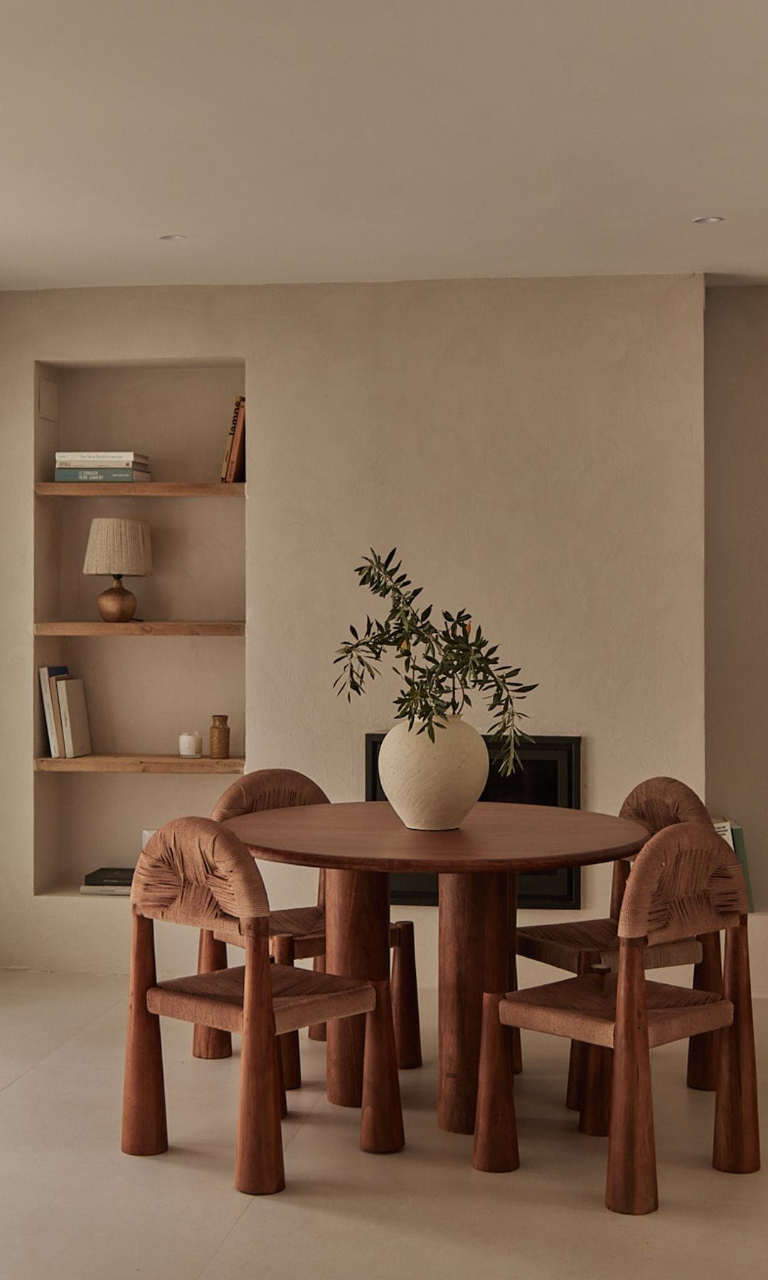 Comedor con mesa redonda y sillas de madera y estantería de obra con baldas de madera