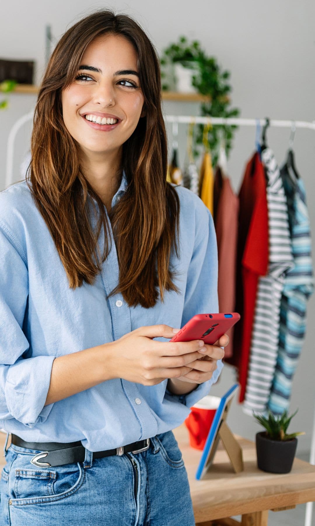 Mujer sonriendo con un teléfono móvil en las manos haciendo compras online