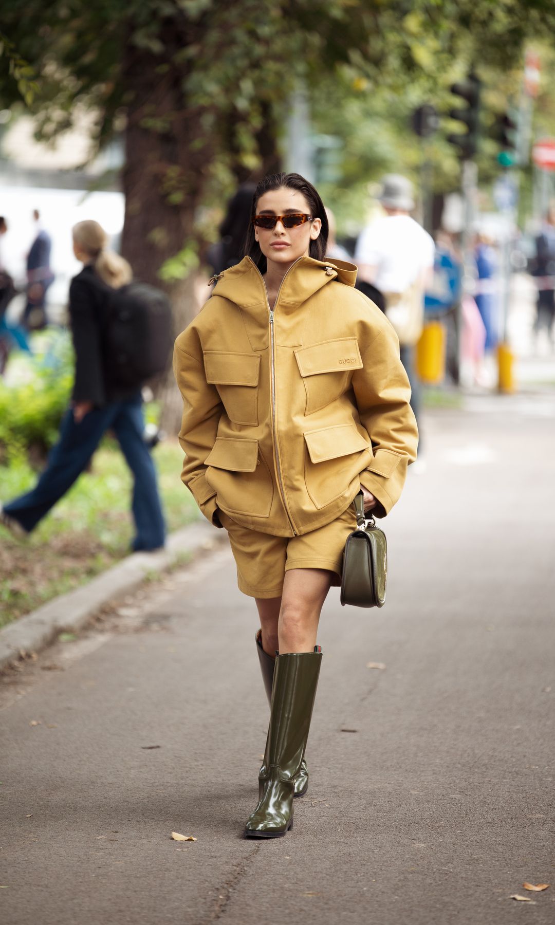 Chaqueta y bermudas mostaza con botas altas y bolso verde oliva