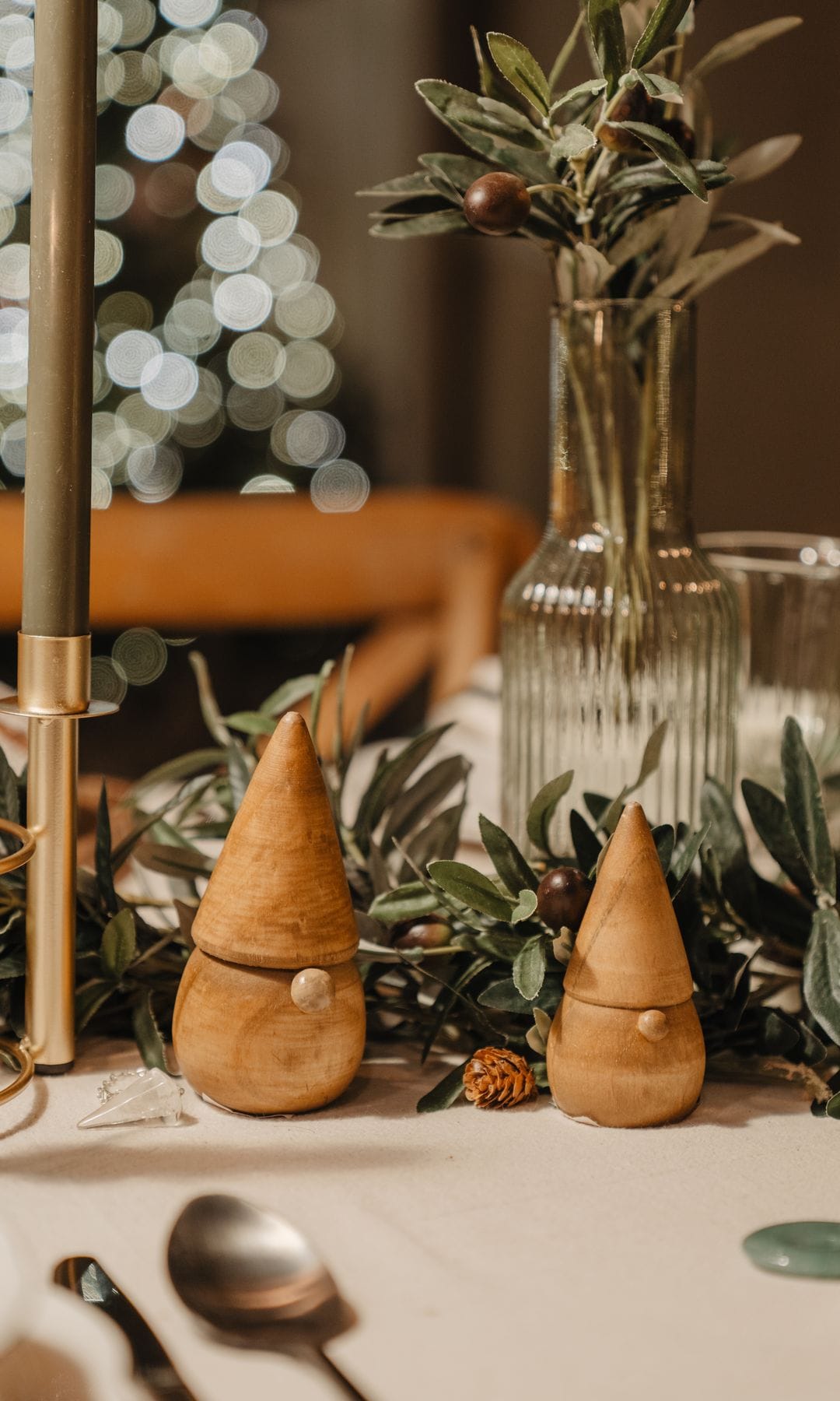 Mesa de Navidad con adornos de madera, ramas de acebo y vela