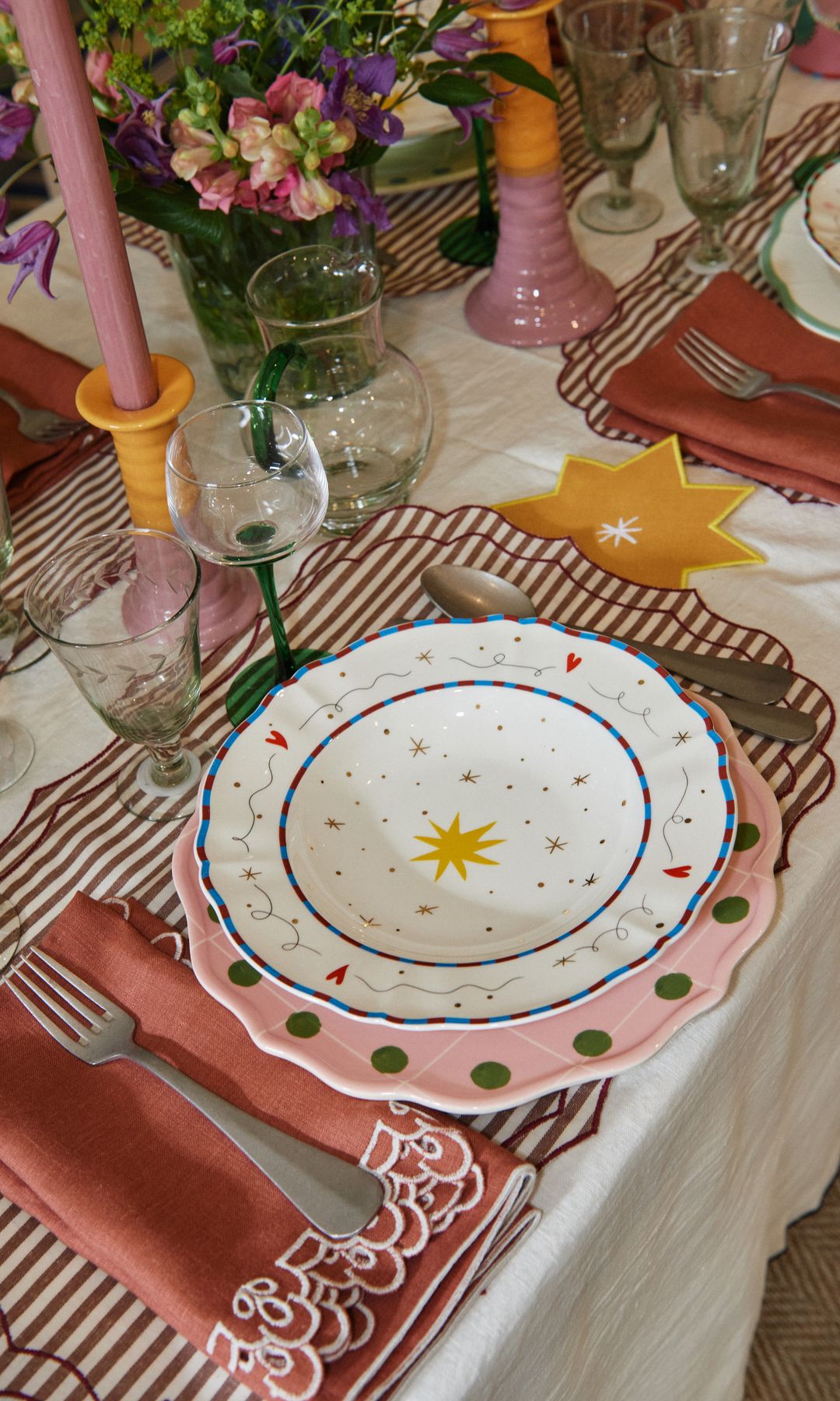 Mesa de comedor decorada con candelabros, platos de estrellas y manteles individuales 