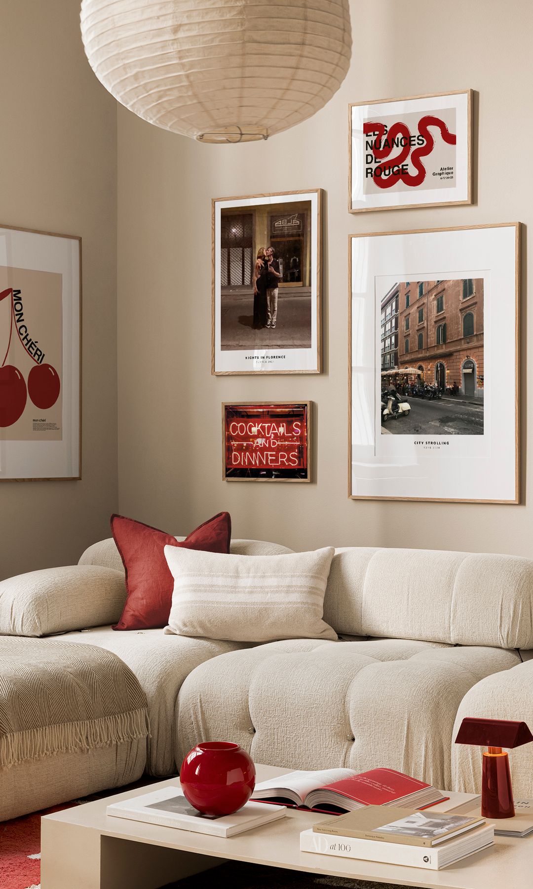 Salón con sofá blanco con chaise longue, mesa de centro blanca y cuadros y adornos rojos