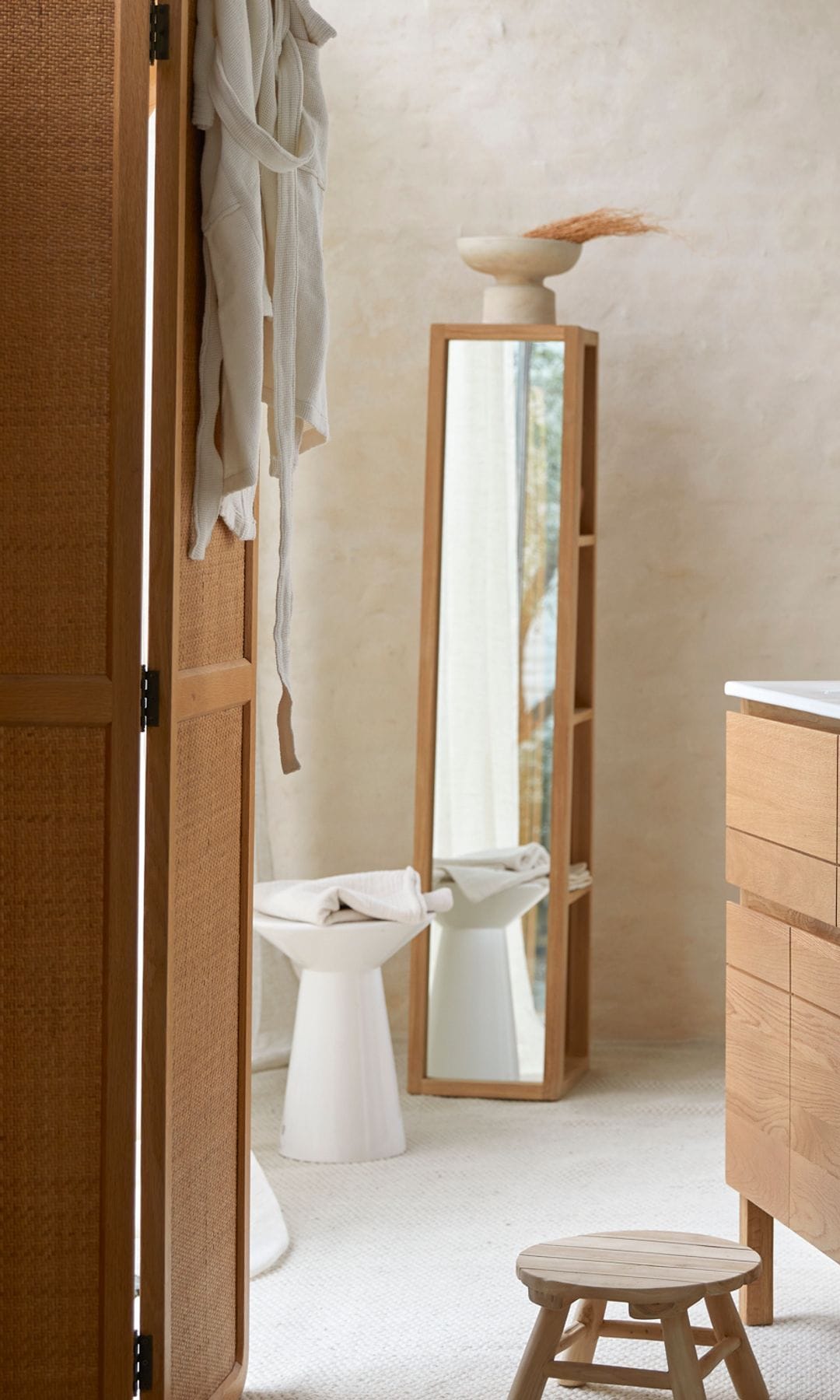 Baño con muebles de madera, biombo y columna con espejo 