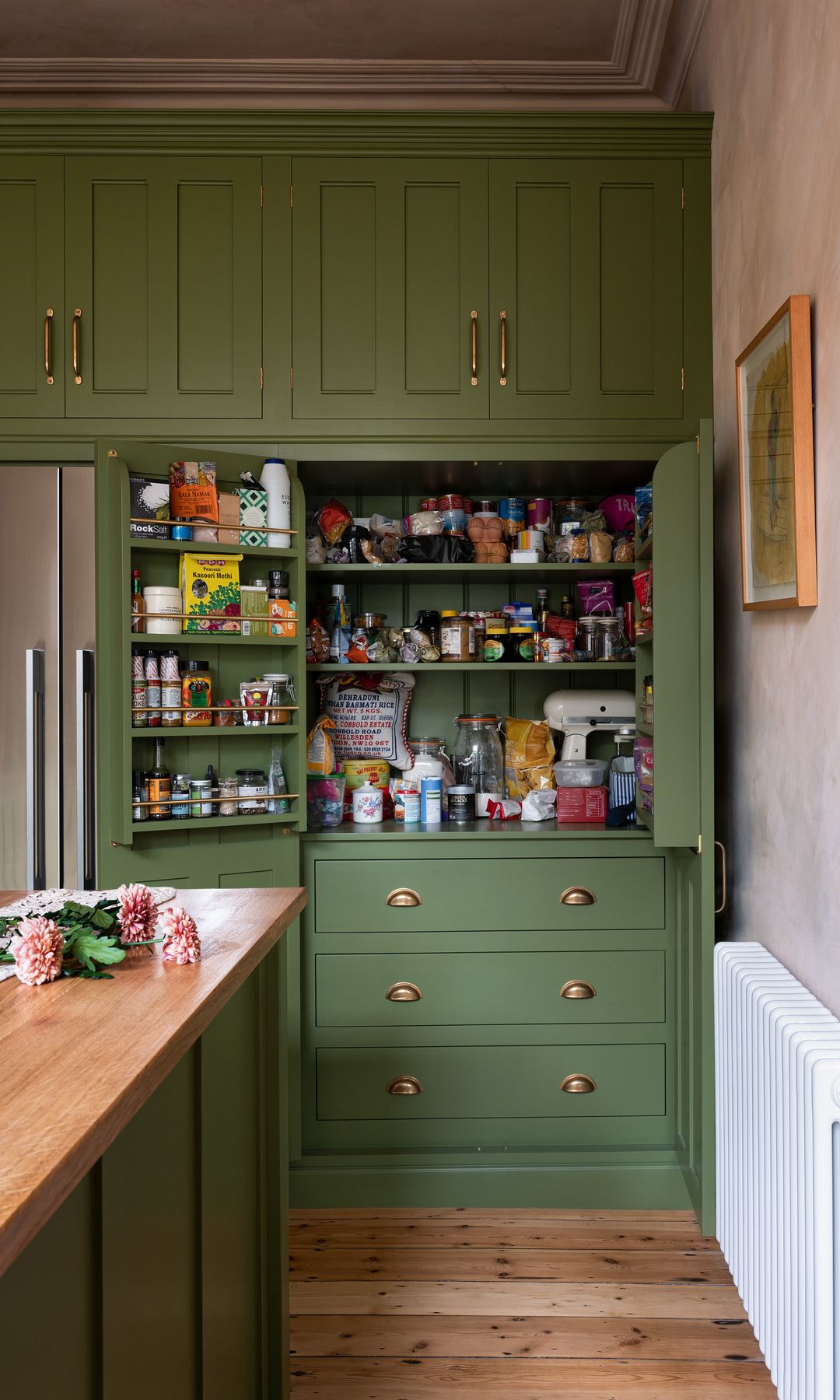 Cocina con suelo de madera, muebles verdes con despensa 