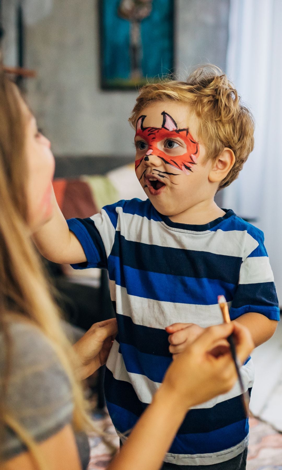 Madre maquillando a su hijo con una máscara de monstruo por Halloween