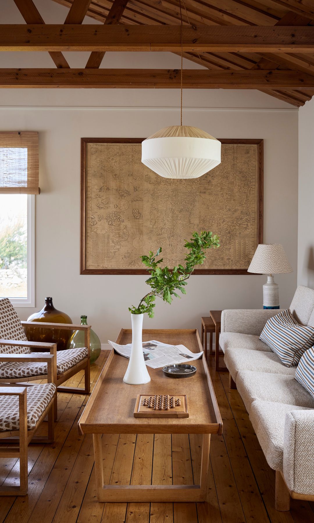 Salón con vigas de madera en el techo, parquet, mesa de centro de madera, sofá blanco