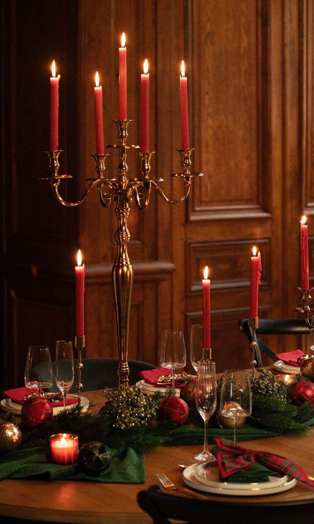 Mesa de Navidad con candelabros rojos, centro de mesa verde y rojo y copas 