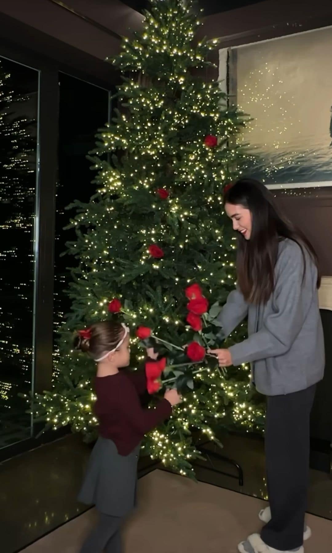 Sharon Fonseca con Blu decorando el árbol con esferas y rosas rojas