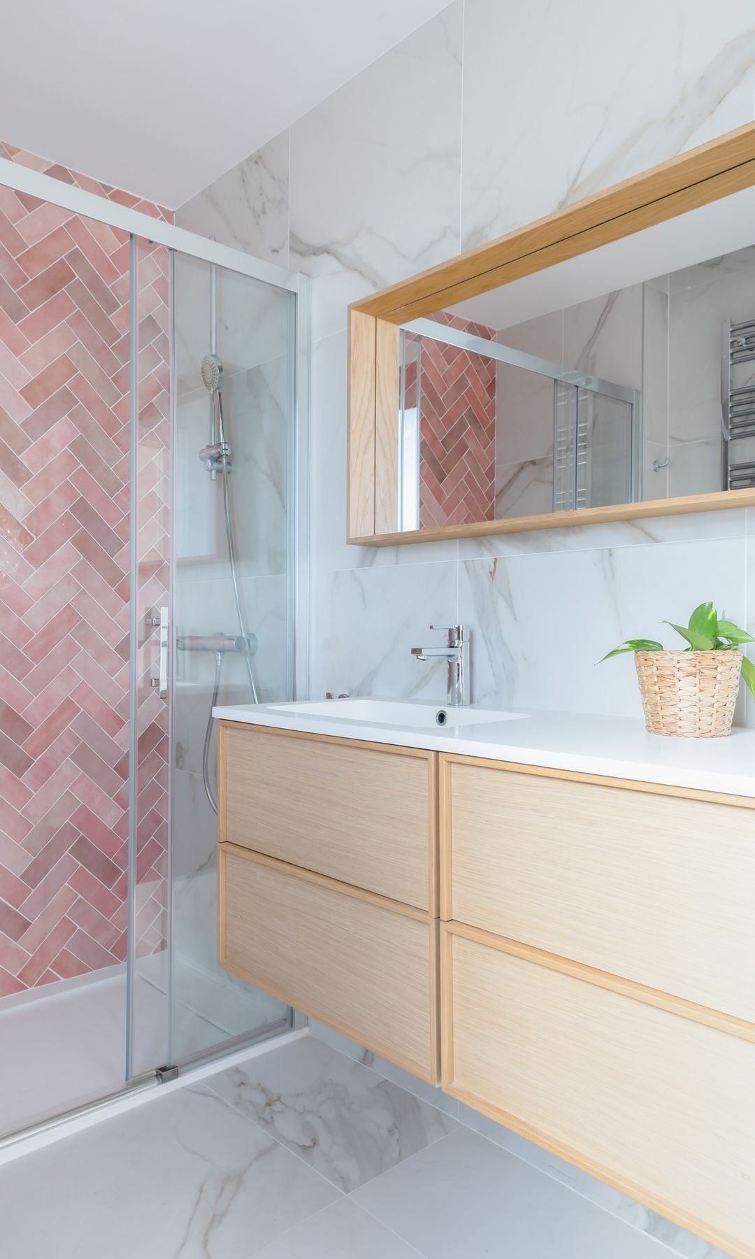 Baño con azulejos en espiga rosas, mueble bajolavabo de madera, espejo de madera y mampara corredera