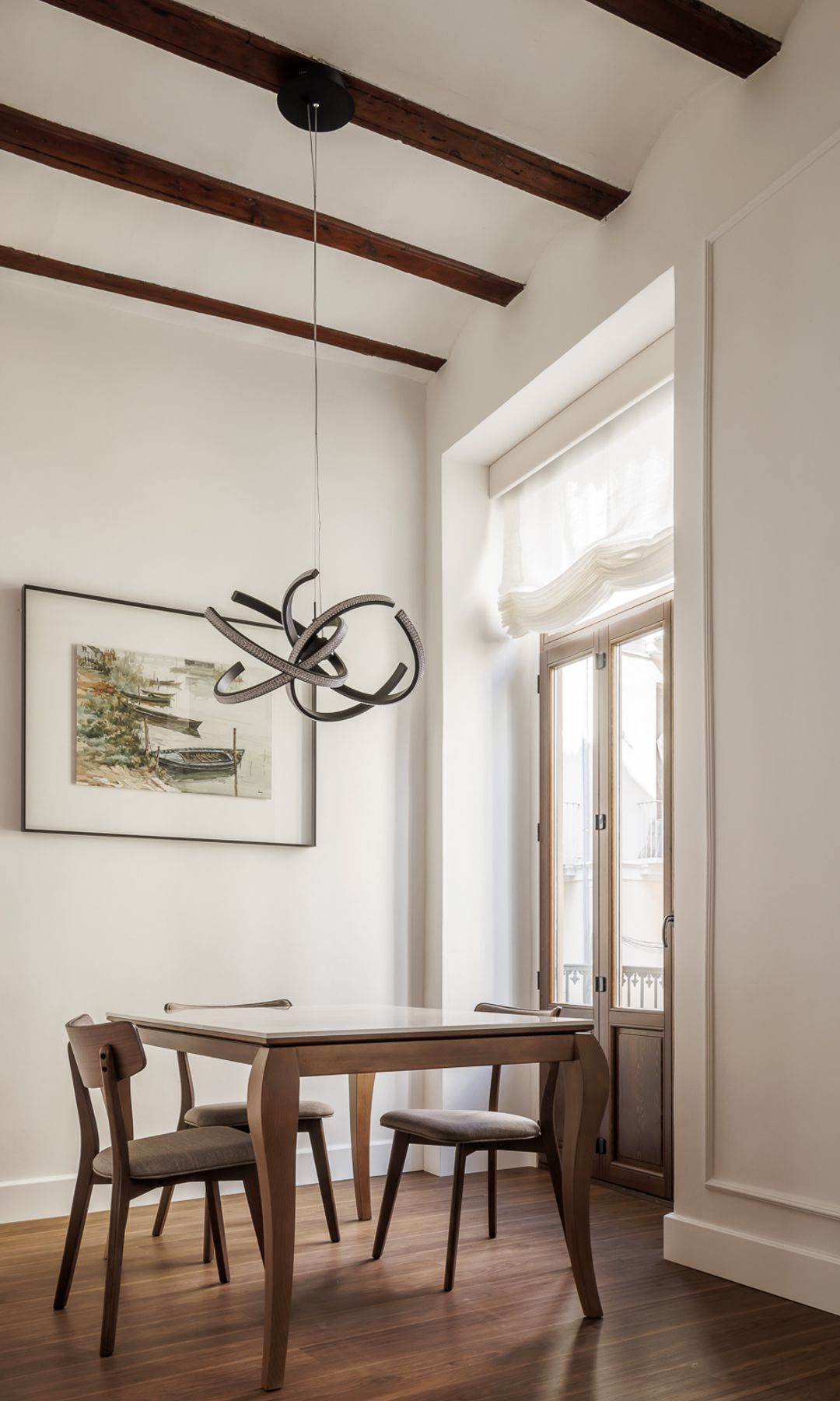 Comedor con vigas, mesa y suelo de madera y lámpara de techo brillante