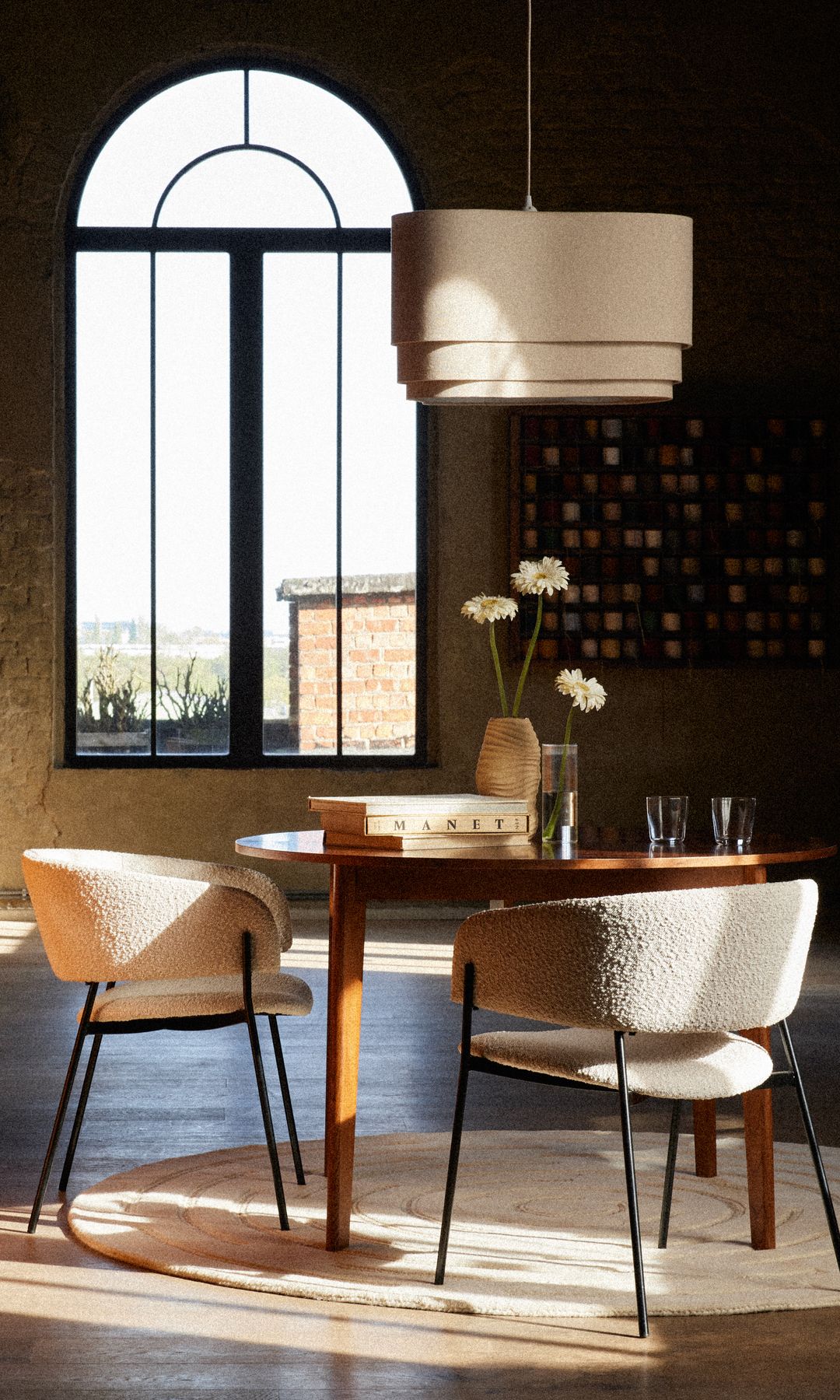 Comedor con mesa redonda de madera, sillas tapizadas con lana bucle, alfombra redonda y mueble de madera