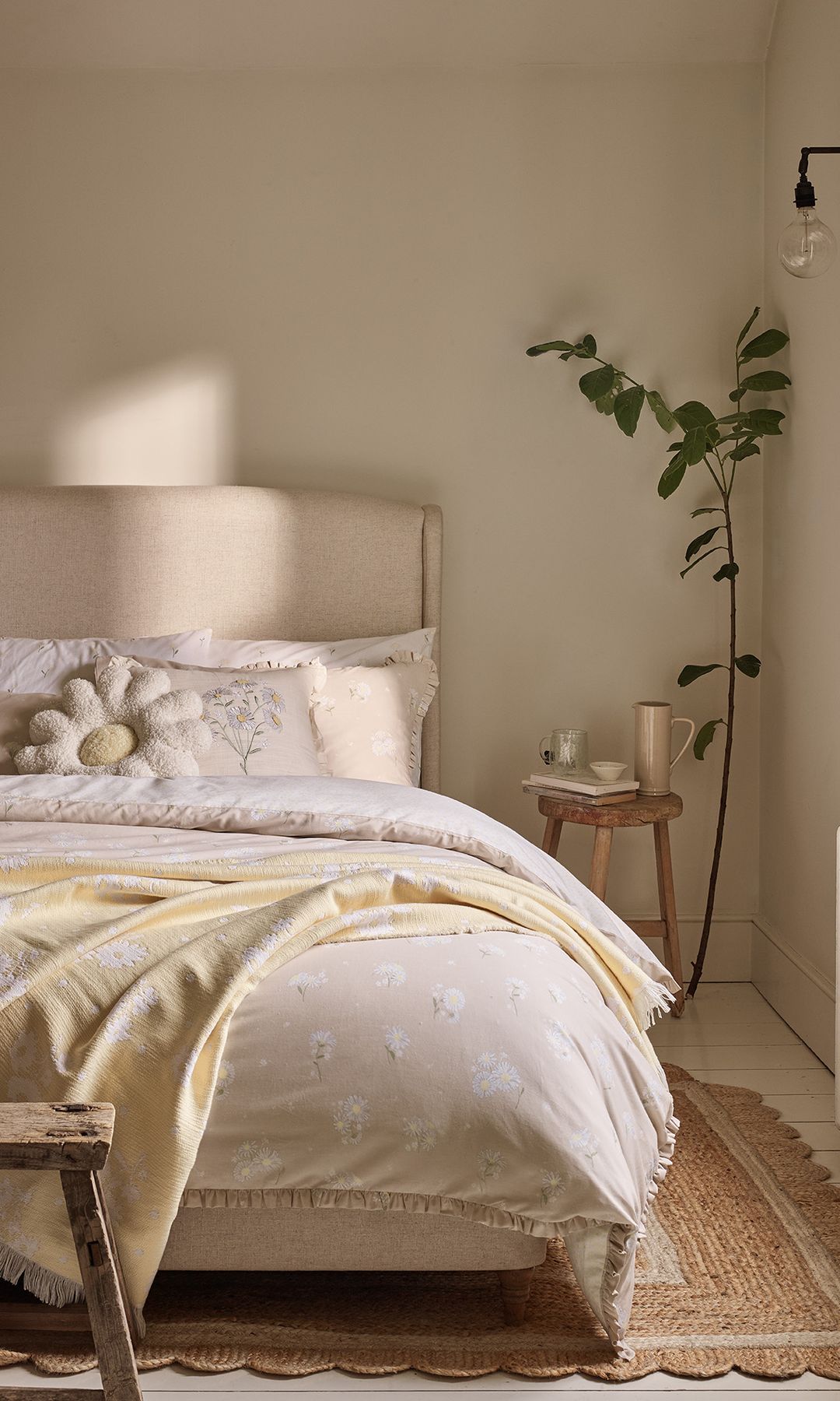 Dormitorio en colores neutros, con taburete de madera y planta