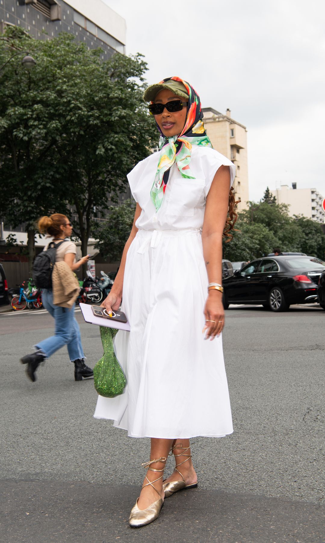  vestido blanco, mini bolso verde con lentejuelas, gorra con pañuelo y gafas de sol negras