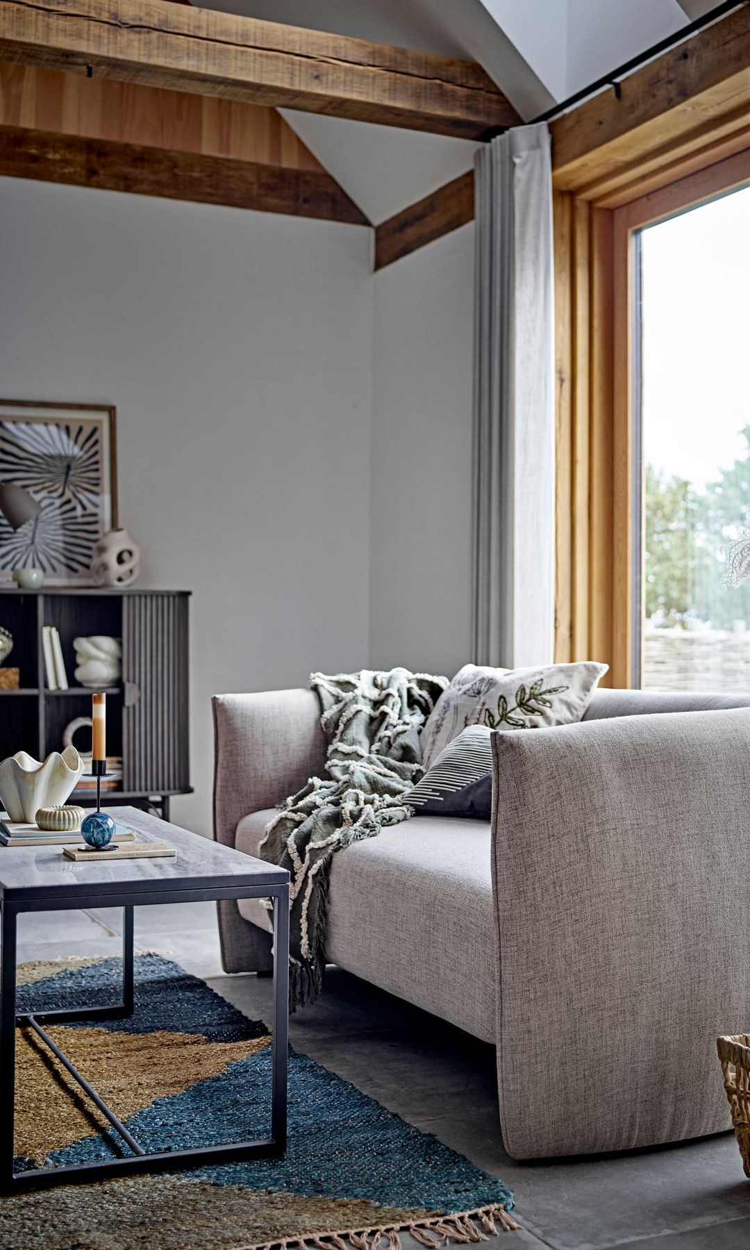 Salón con carpintería de madera, sofá gris, mesa de centro de hierro y alfombra azul 