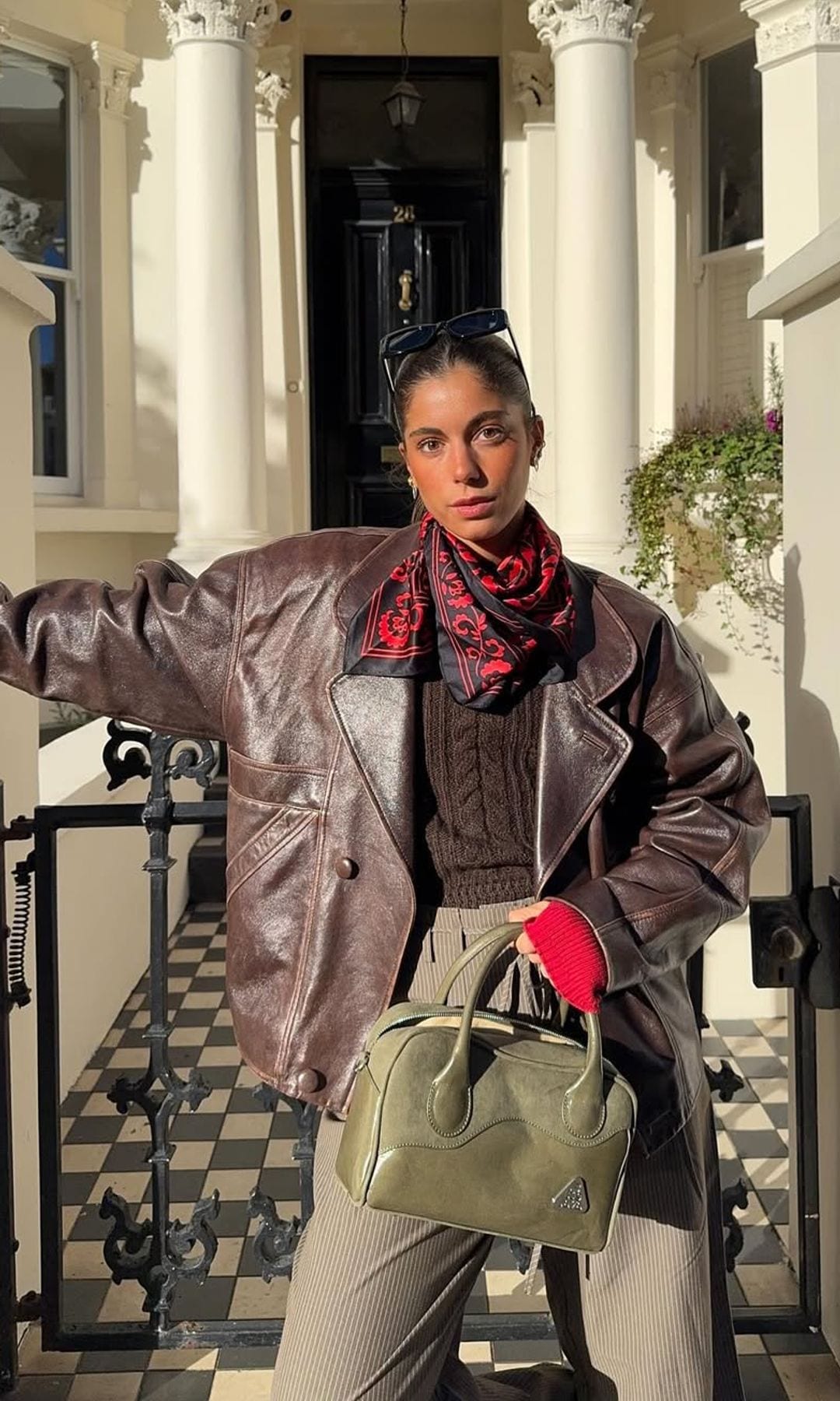 chaqueta de cuero marron con pantalones verde oliva y accesorios rojos