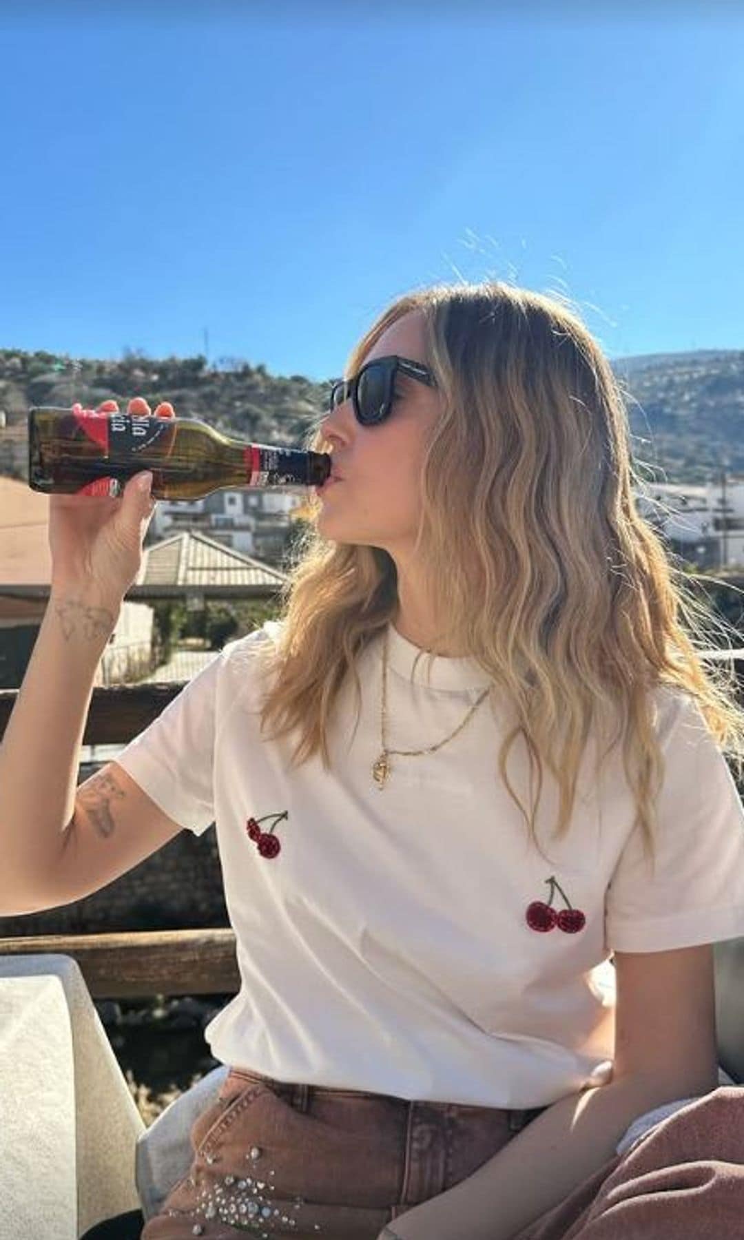 Chiara Ferragni con vaqueros rosas con detalle de strass y camiseta blanca con cerezas bordadas bebiendo cerveza en Granada