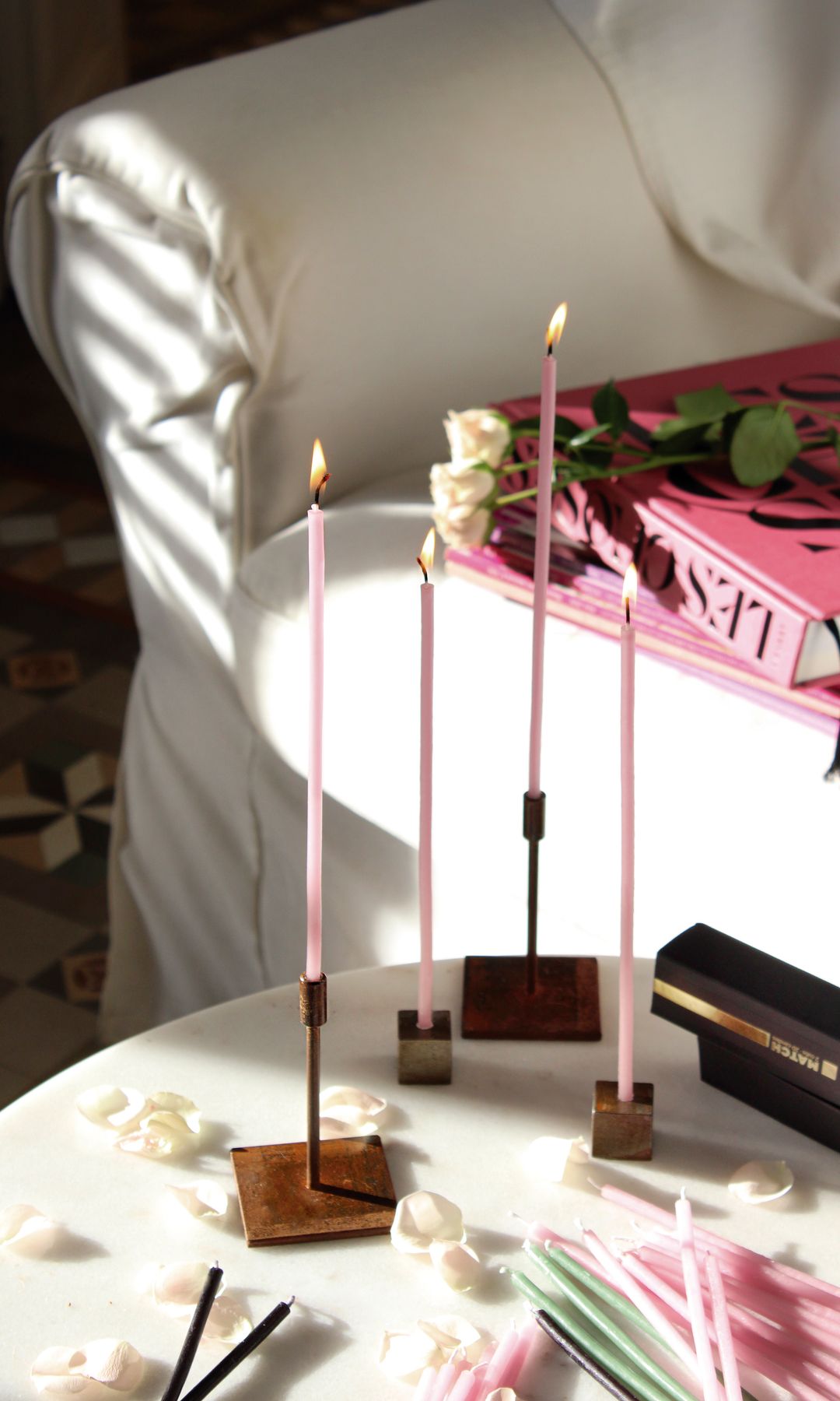 Salón con sofá blanco, libro rosa y candelabros rosas