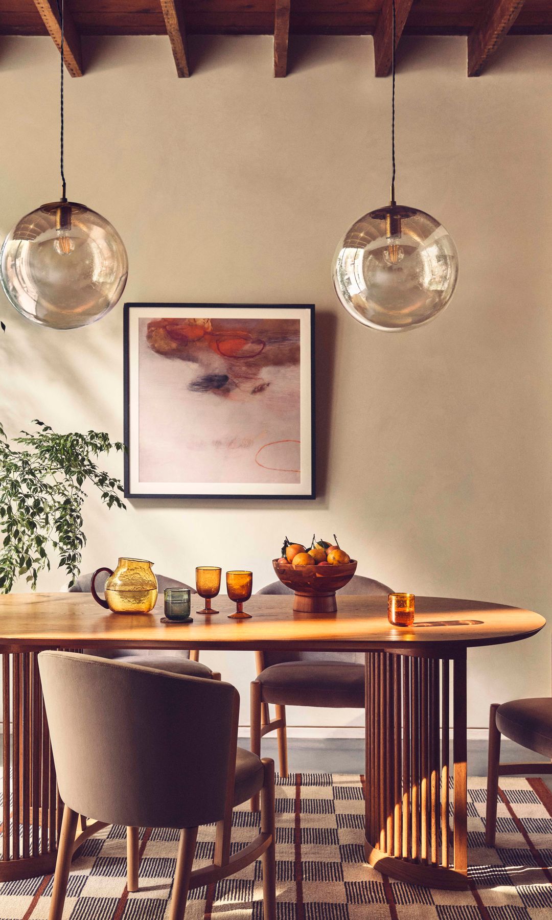 Comedor con mesa ovalada de madera, lámparas redondas de cristal de techo y alfombra de cuadros