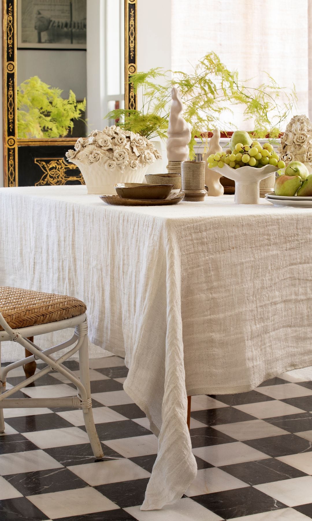 Detalle de una zona de comedor con mantel blanco y suelo en damero