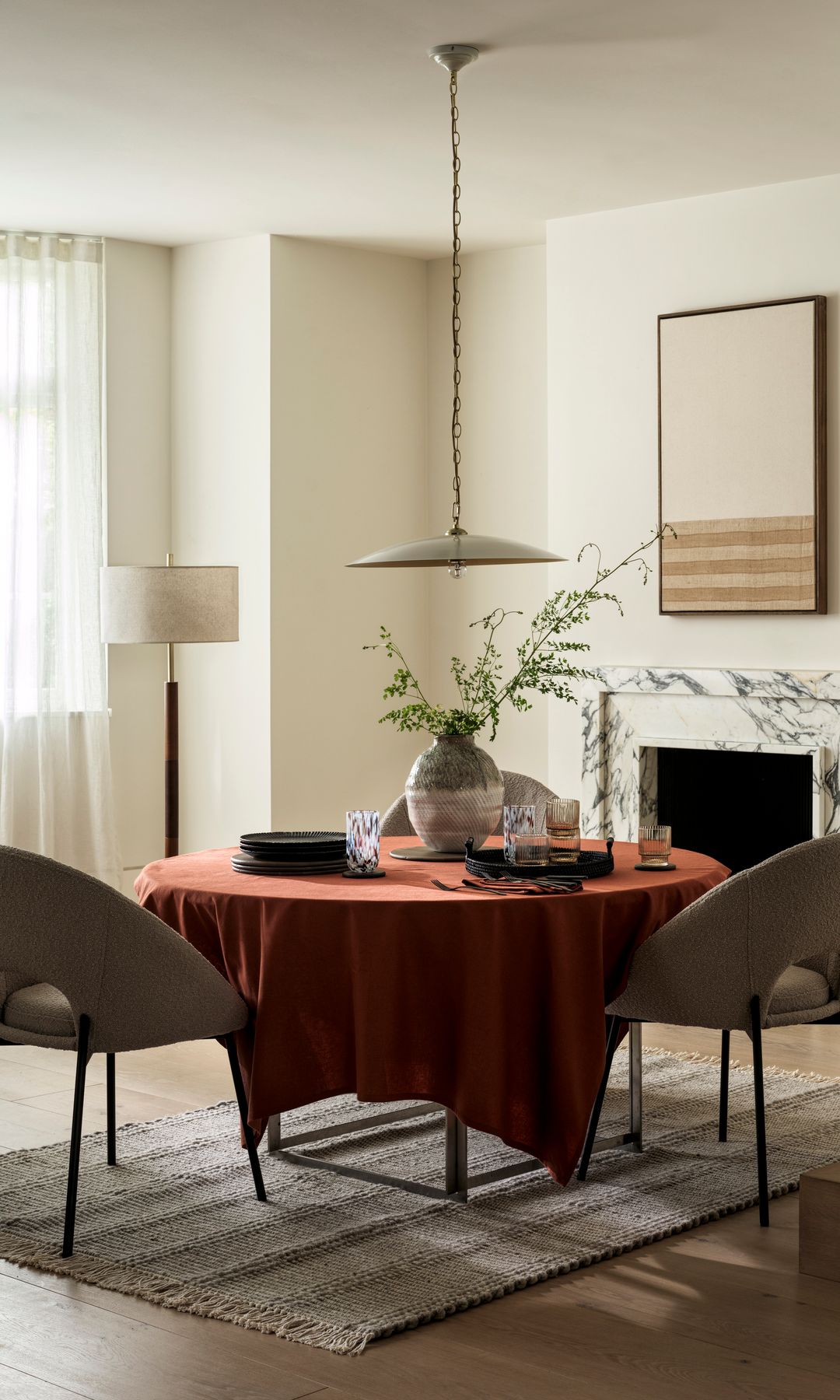 Comedor con chimenea de mármol, mesa redonda, mantel burdeos y alfombra