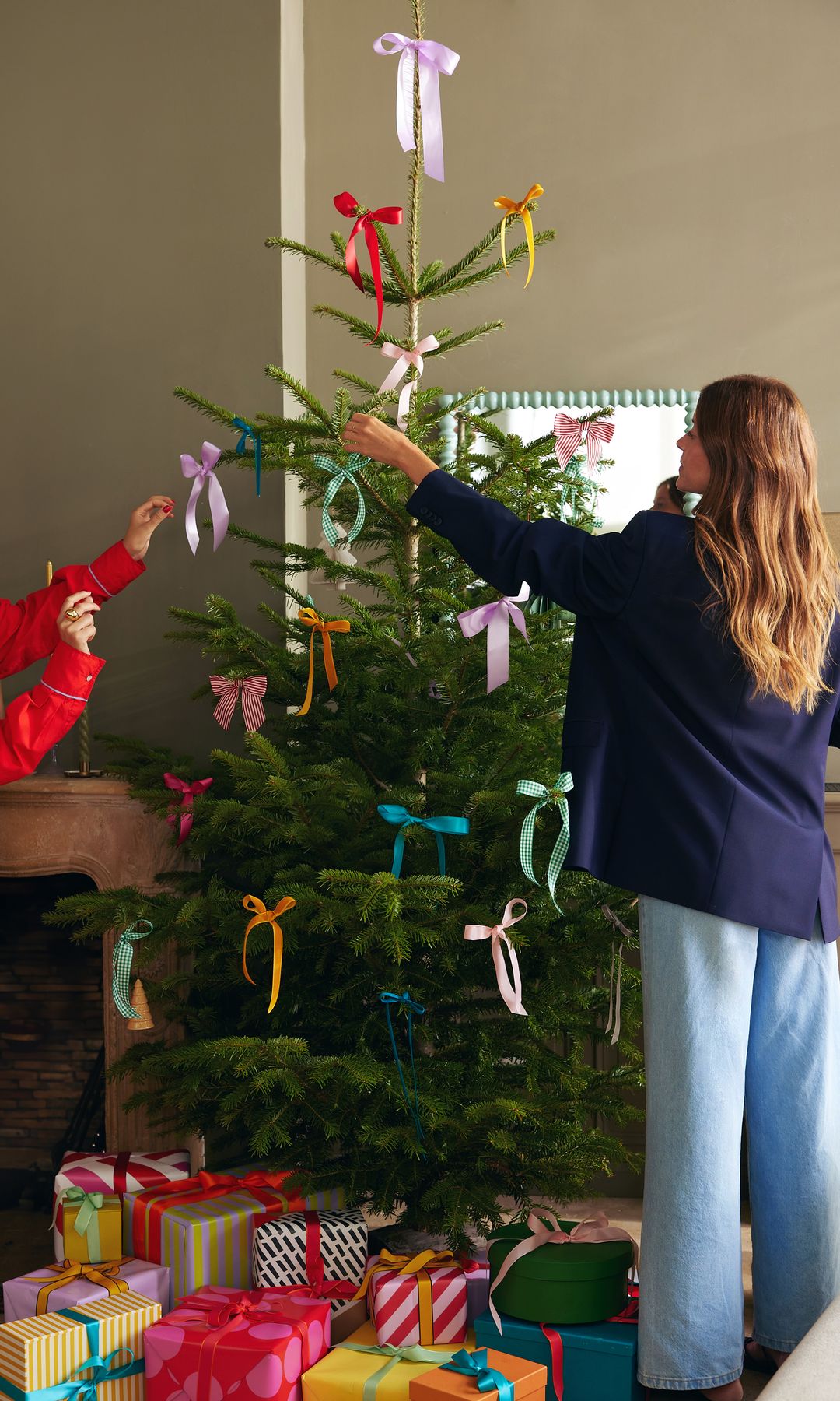 Mujer decorando un árbol de Navidad con lazos