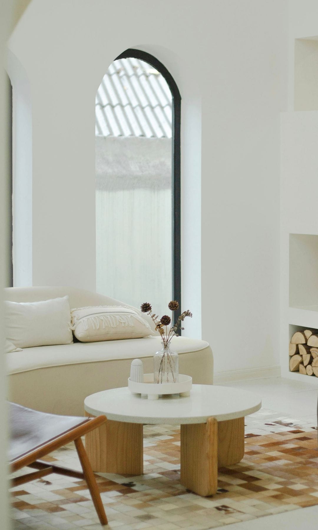 Salón blanco de estilo rústico con sofá blanco, mesa de centro redonda y librería de obra