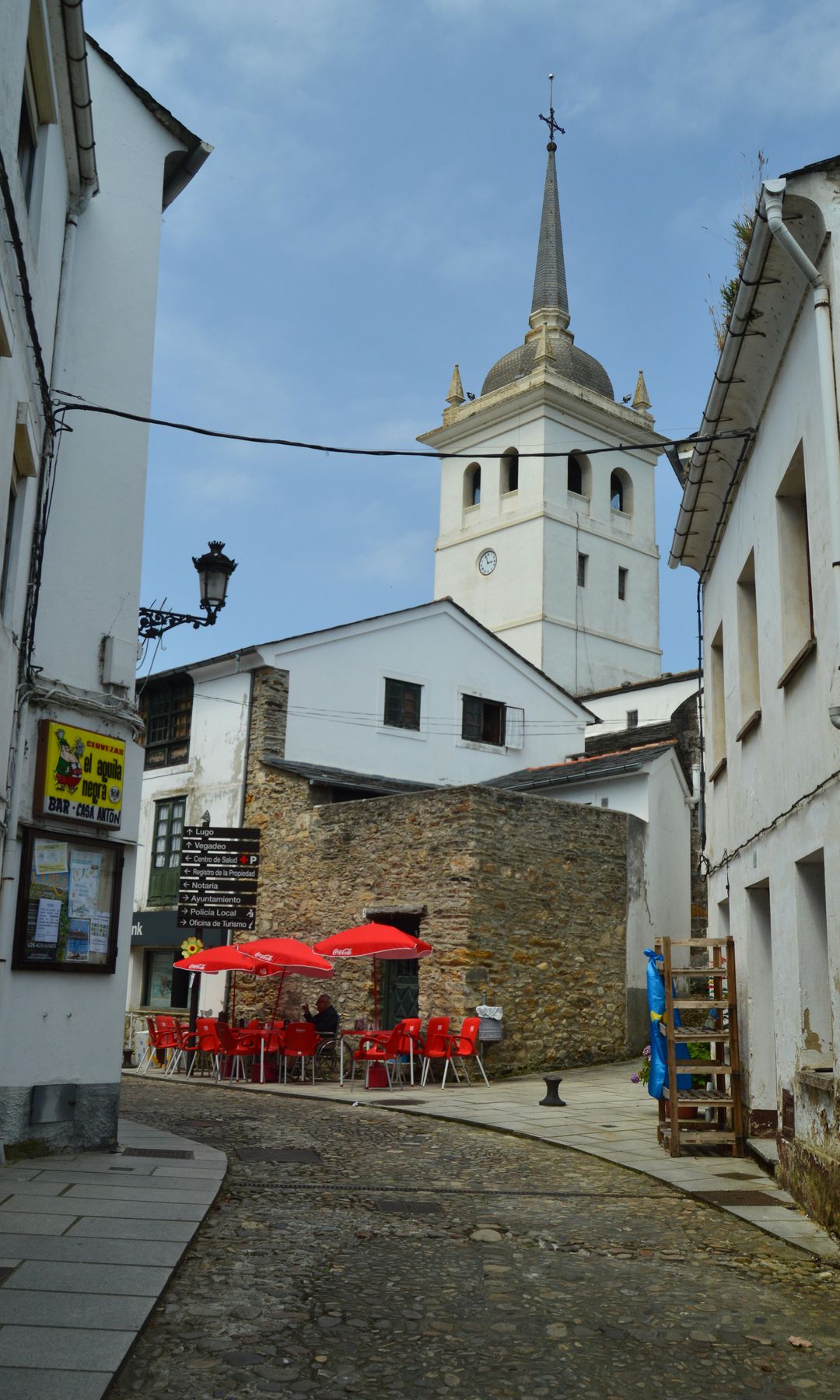 Pintorescas, estrechas, curvas y cuesta arriba calles de Castropol con el campanario de la iglesia de Santiago Apóstol al fondo