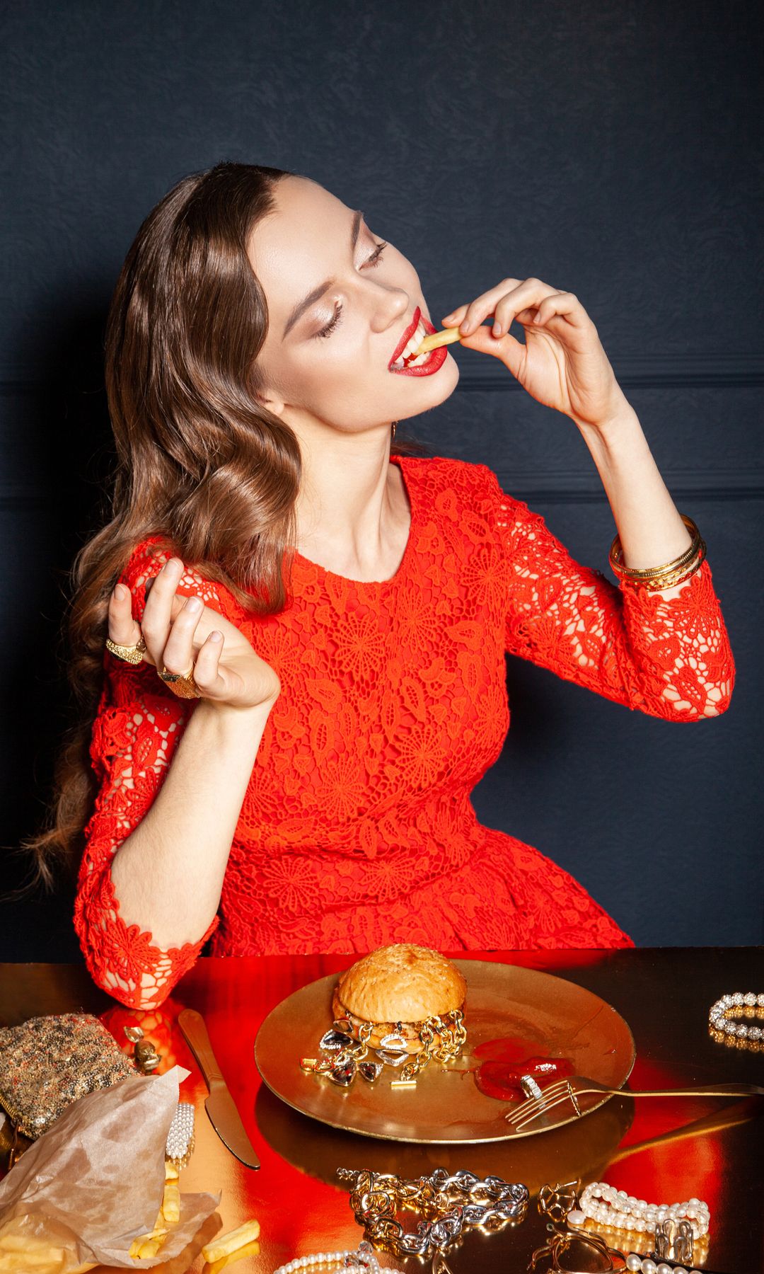 Mujer vestida de rojo comiendo una hamburguesa con patatas fritas